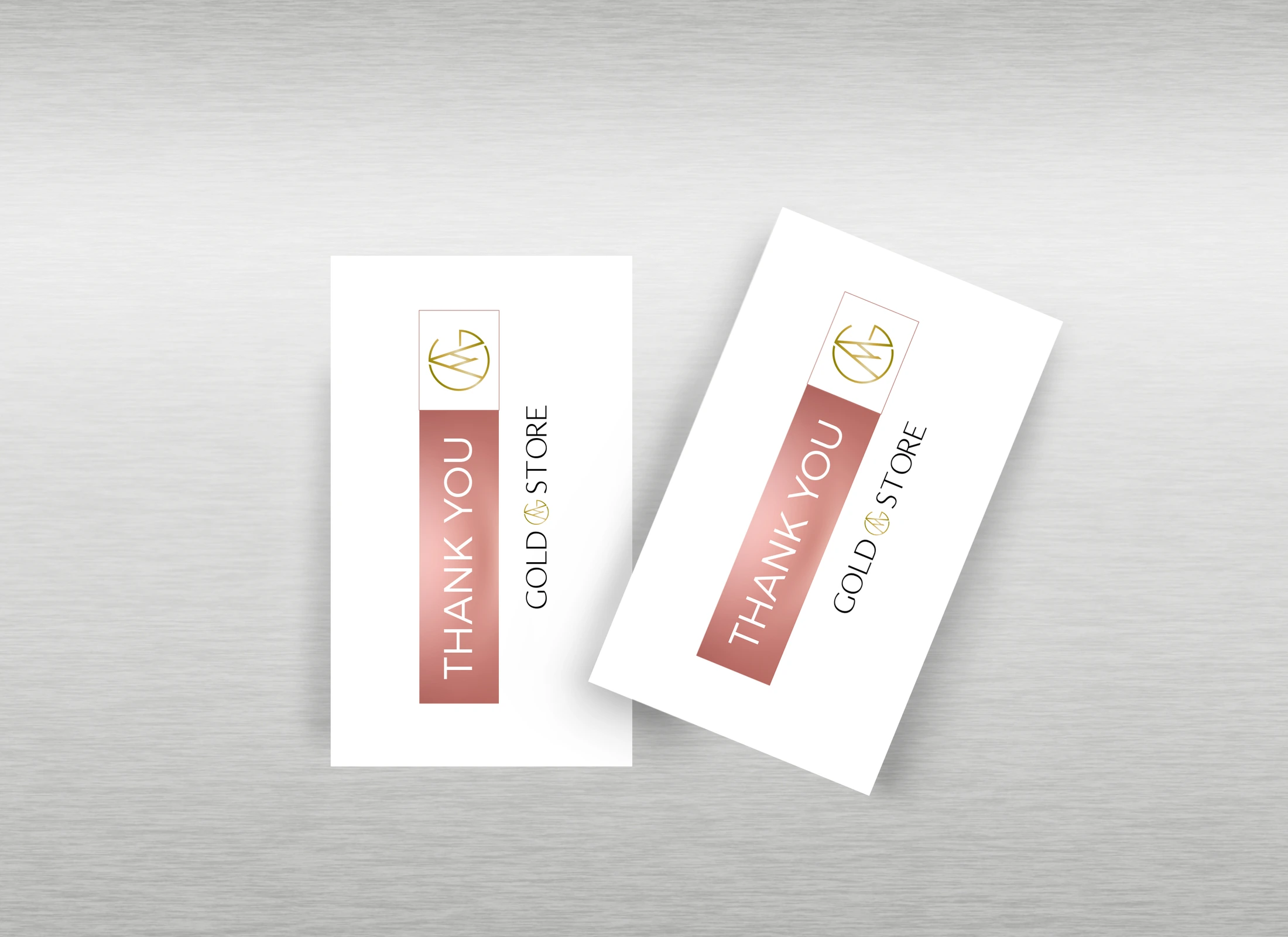 Maqueta de dos tarjetas de agradecimiento Gold Store sobre una superficie gris, con logotipo dorado y una franja rosa.